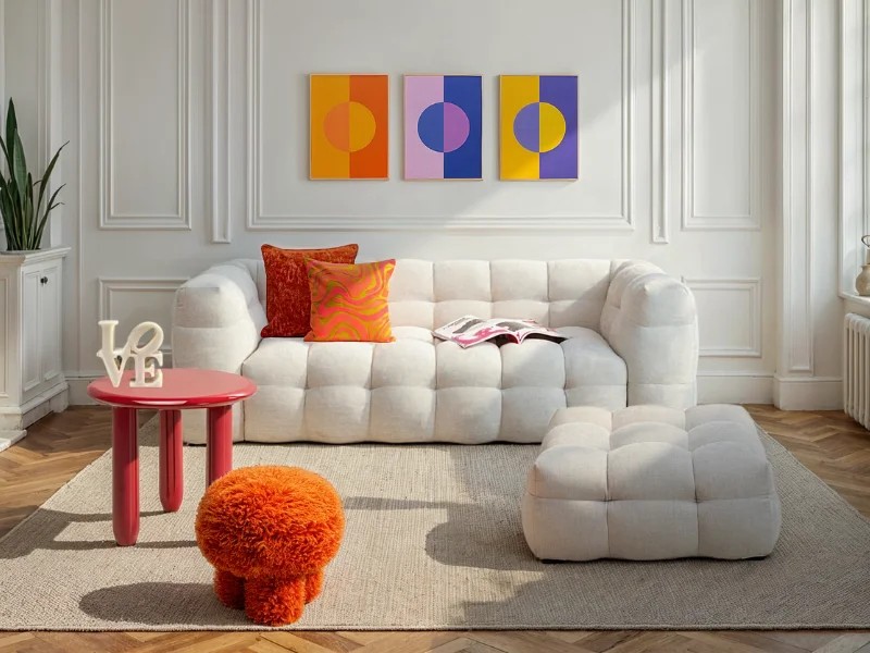 Modernes Wohnzimmer mit hellem Sofa, farbigen Kissen, Bildern und roten Wohnaccessoires von KARE