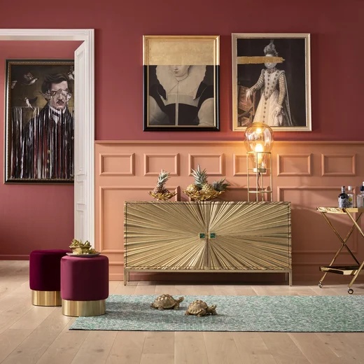 Elegante KARE Kommode mit goldfarbenen Fronten in einem Wohnraum mit dunkler Wand und gerahmten Bildern.