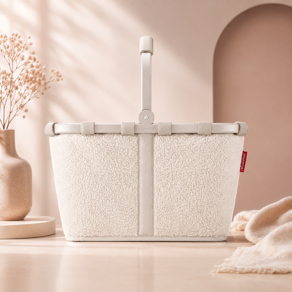 Cremefarbener Reisenthel Carrybag in Teddy-Optik mit stabilem Klappgriff vor hellem Hintergrund.